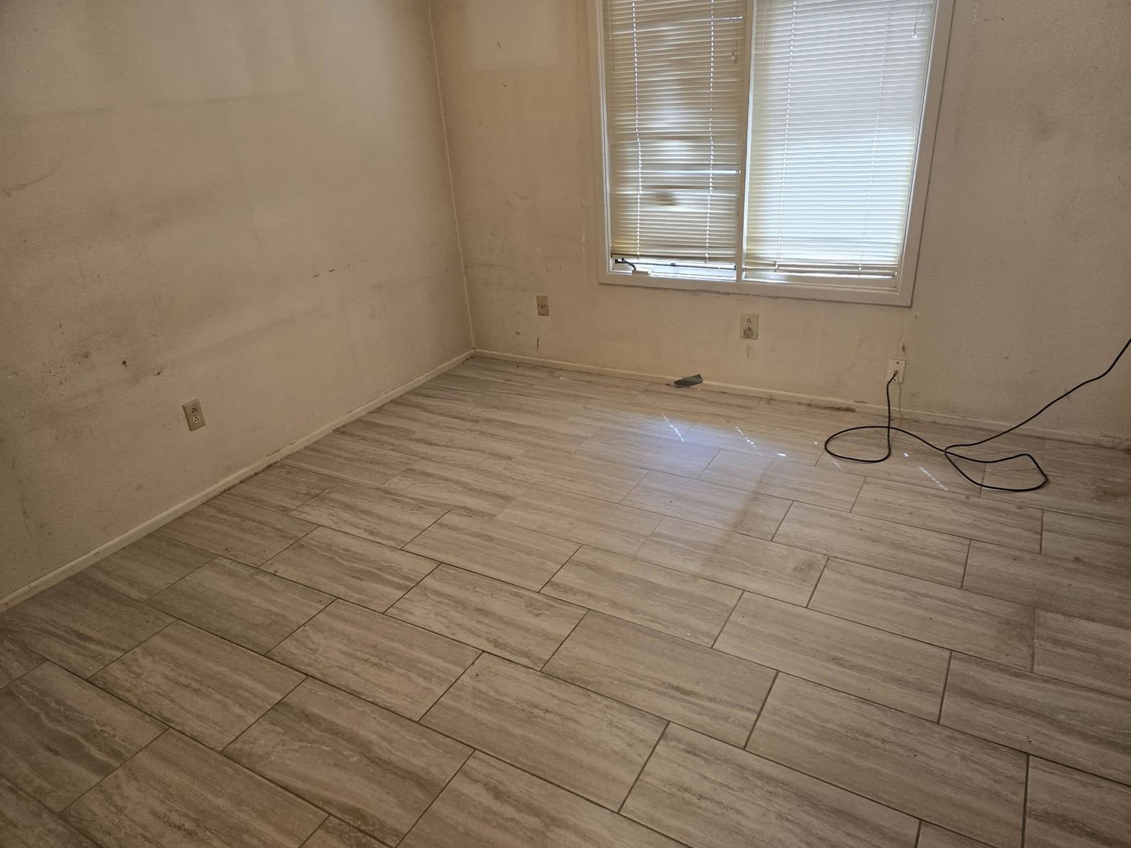 Empty room after an 806 Cleanouts cleanout: bare tile floor, plain walls, and a window with blinds